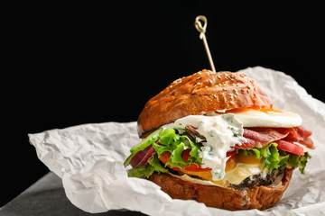 Tasty burger with fried egg on table against black background