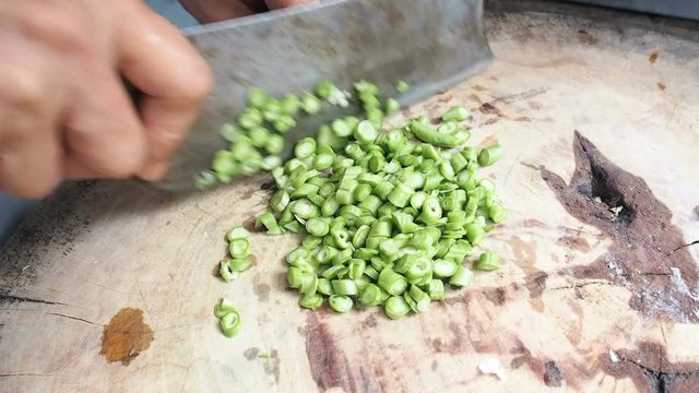 Chopping fresh green long bean close up on a wooden board in asian kitchen