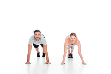 Obraz na płótnie Canvas cheerful athletic couple doing push ups together isolated on white
