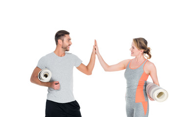 athletic couple with yoga mats giving five to each other isolated on white