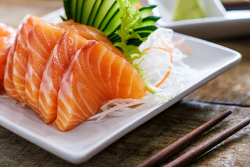 Sashimi, Salmon, Japanese food chopsticks and wasabi on the wood table
