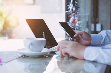 attractive hand man using smartphone and laptop working with coffee cup in coffee shop.