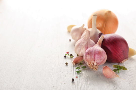 Fresh garlic, onion and pepper grains on light background