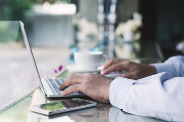 attractive business man hand using laptop working with coffee cup in coffee shop.