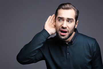 Young man with hearing problem on grey background