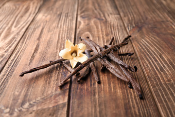 Vanilla sticks and flower on wooden background