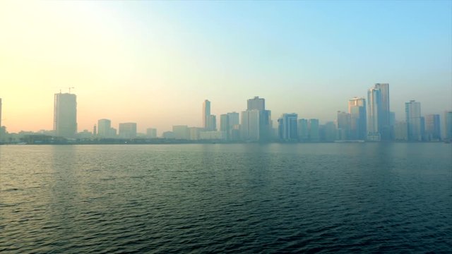 Urban background, morning cityscape with skyscrapers, blue sky reflecting in blue sea and big metropolis.