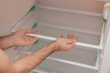 Male technician installing shelf of refrigerator, closeup