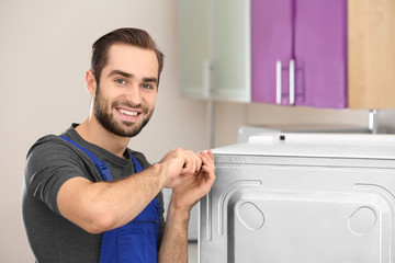 Male technician repairing refrigerator indoors