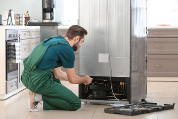 Male technician repairing refrigerator indoors