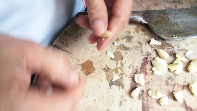 Peeling clove on wooden cutting board in asian kitchen