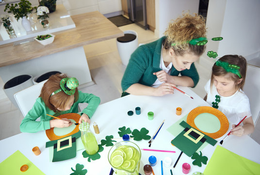 Mother with children preparing decorations for Saint Patrick's Day.