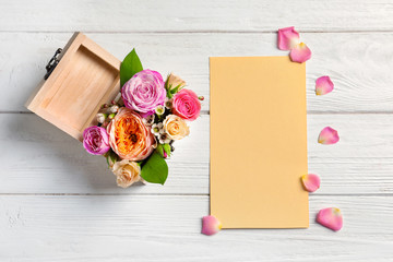 Empty card and box with flowers on wooden background