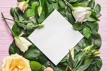 Beautiful flowers, foliage and empty card on wooden background
