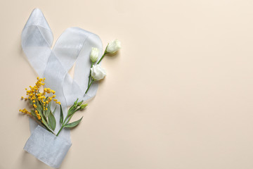 Beautiful flowers and ribbon on light background