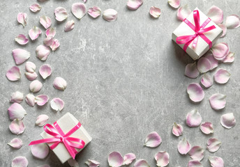 Gift boxes and petals on grey background