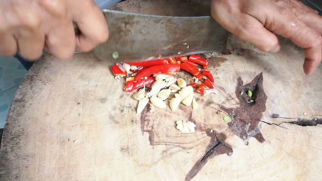Chopping red chilli and garlic prepare for home cooking on wooden board close-up view