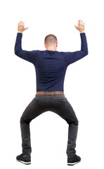 back view. man  protects hands from what is falling from above.