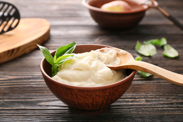 Mashed potatoes and spoon in bowl on wooden table