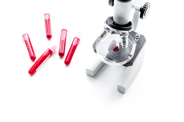 Blood test concept. Blood samples near microscope on white background top view copy space