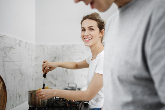 Beautiful smiling Caucasian woman enjoying cooking with her boyfriend.