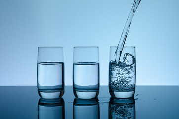 Creative splashing water in the glass on blue background.