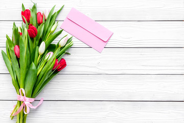 First spring flowers. Bouqet of delicate tulips on white wooden background top view copy space