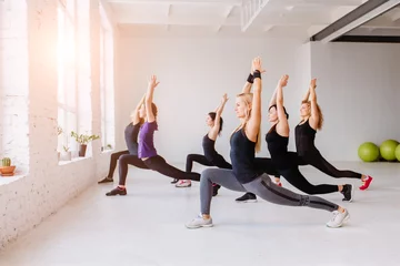 Zelfklevend Fotobehang Group of women doing yoga, pilates and fitness and exercise indoors in white loft interior studio. © Iryna