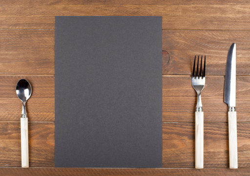 Empty black paper between covered kitchen on wooden table. Menu. Food