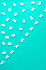 Fototapeta na wymiar White sugar cubes arranged in diagonal lines on blue background