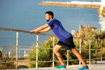 fit young man stretching muscles by the sea