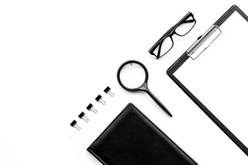 Monochrome white and black work desk with pad, notebook, glasses on white background top view copy space mock up
