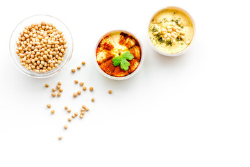 Fototapeta na wymiar Middle Eastern cuisine. Bowls with hummus and chickpeas on white background top view copy space