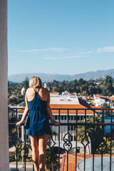 Fototapeta na wymiar Blonde Woman in Blue Dress Looking Over City
