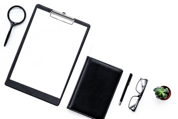 Strict work desk with pad, glasses, magnifiger, notebook, plant on white background top view copy space mock up