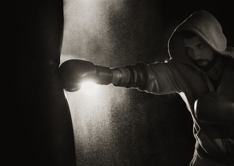 Young professional boxer training with punching bag in gym