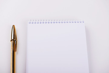 Notepad with blank paper next to golden ball pen on white background. Isolated. Mockup.