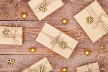 Fototapeta na wymiar homemade wrapped christmas and new year present boxes and decoration on wooden background. holiday and celebration concept. above view, flat lay.