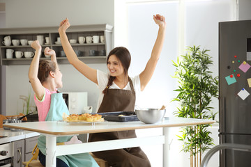 Mother and daughter having fun while preparing dough indoors