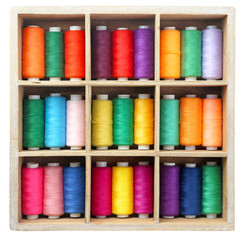 Set of color sewing threads in wooden compartment box on white background