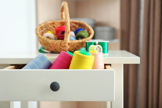 Set of color sewing threads in drawer of small table indoors