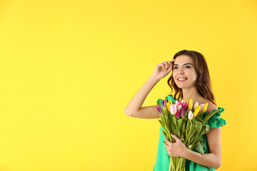 Beautiful woman holding bouquet of tulips on color background