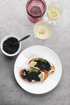 Slices of bread with black caviar and butter on plate