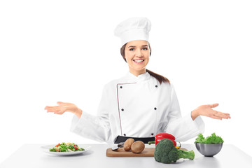 Female chef near table with products against white background