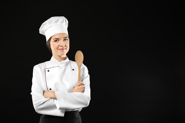 Naklejka premium Portrait of female chef with wooden spoon on black background