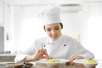 Female chef preparing tasty pasta in kitchen