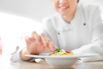 Female chef preparing tasty pasta in kitchen, closeup