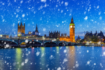Big Ben and Westminster bridge on a cold winter night with falling snow, London, United Kingdom