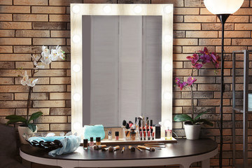 Decorative cosmetics and tools on dressing table near mirror in makeup room