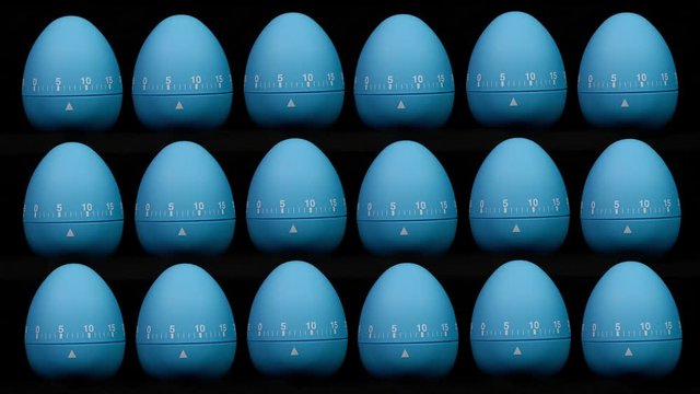 A pattern of multiple kitchen egg timers all counting down to zero. Time lapse.